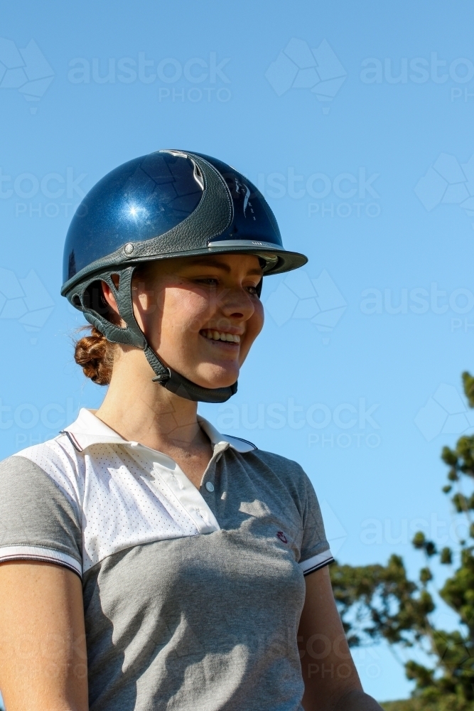 Close up portrait of happy young female horse rider wearing helmet - Australian Stock Image