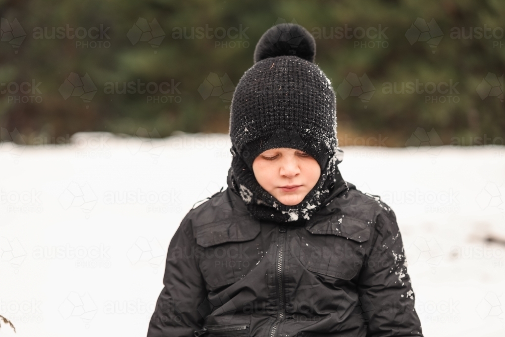 Close up portrait of young boy playing in snowy winter wonderland - Australian Stock Image