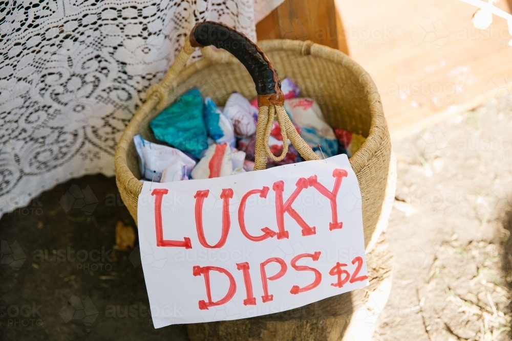 Close up shot of a basket with cloth inside and a signage that says lucky dips $2 - Australian Stock Image