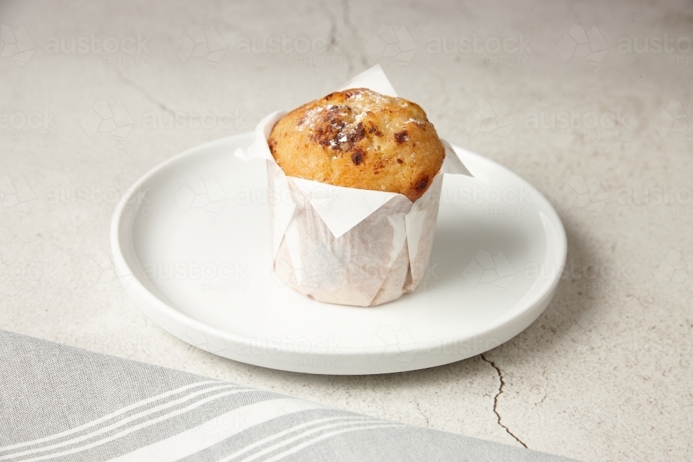 close up shot of a chocolate muffin on a white plate - Australian Stock Image