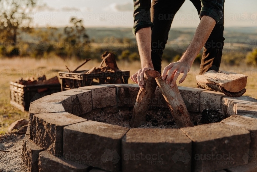 Close up shot of a man preparing pieces of wood for a camp fire place. - Australian Stock Image