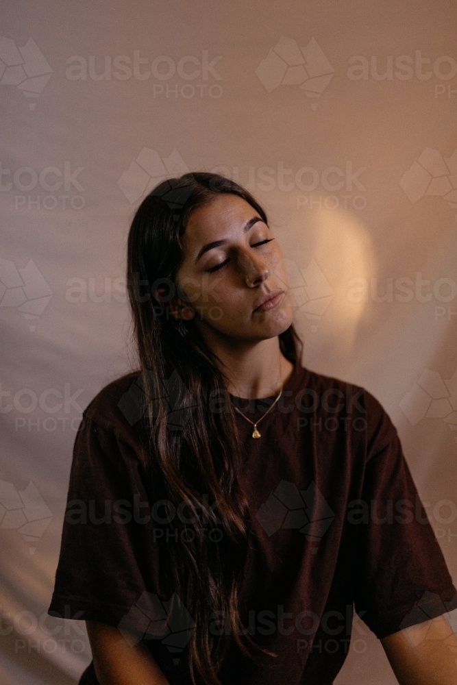 Close up shot of a peaceful woman with long hair with closed eyes - Australian Stock Image