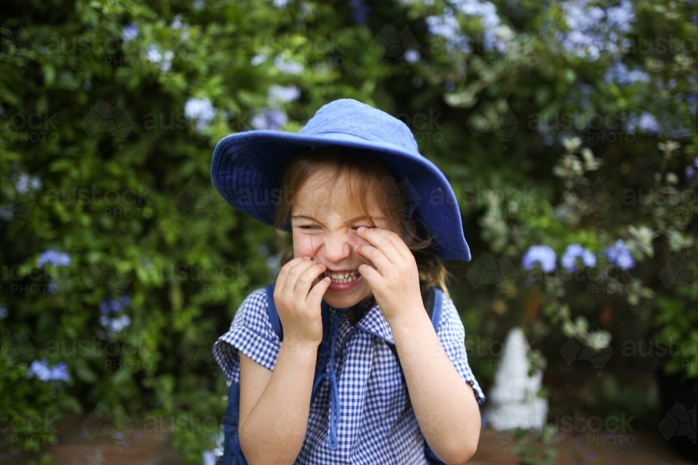 Close up shot of a school girl in uniform with hat and silly face - Australian Stock Image