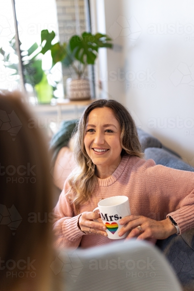 Close up shot of a smiling woman holding a white mug with pride symbol - Australian Stock Image
