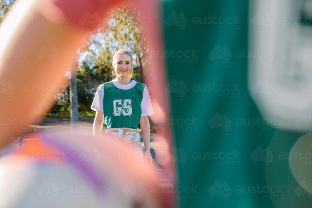 close up shot of a young woman framed in a blurry arm and net ball in the foreground - Australian Stock Image