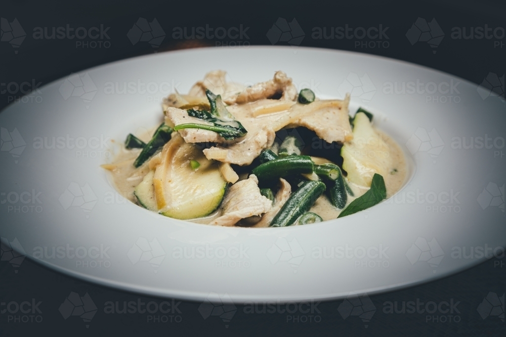 Close up shot of green curry chicken in a white plate - Australian Stock Image