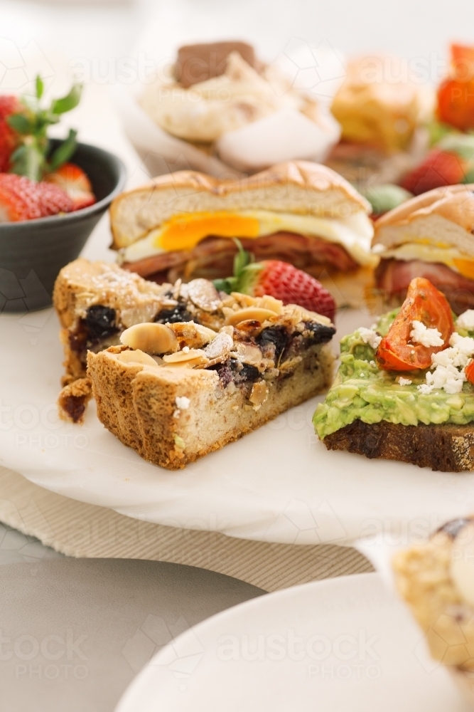 Close up shot of slices of pies, half a sandwich and a bowl of strawberries. - Australian Stock Image