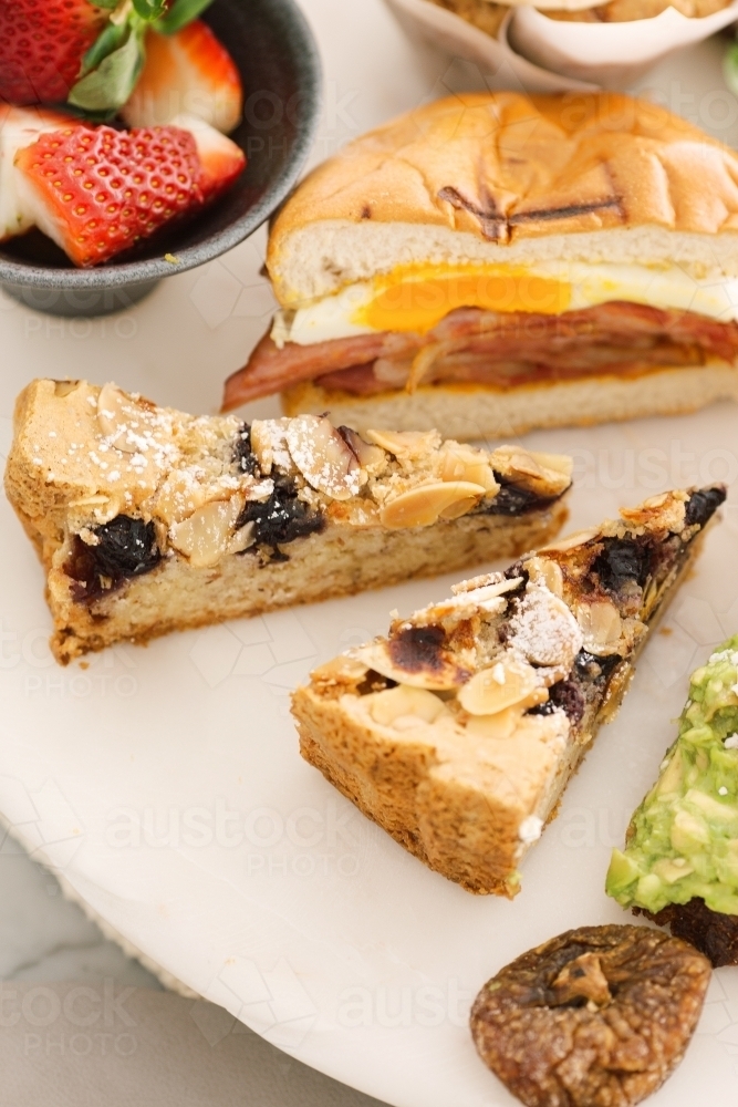 Close up shot of slices of pies, half a sandwich and a bowl of strawberries. - Australian Stock Image