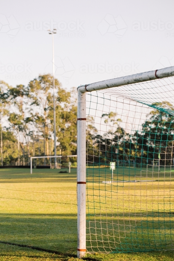 Close up shot of the corner of soccer goal post and net in a big green field - Australian Stock Image