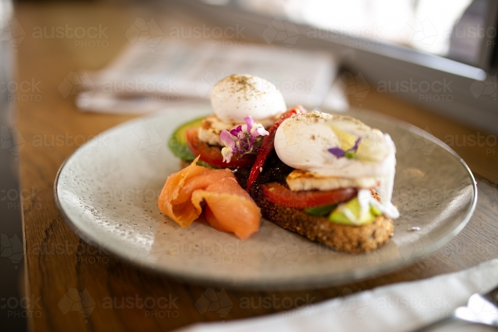 Close up shot of  toast with poached eggs, avocado, tomatoes and salon on a plate - Australian Stock Image