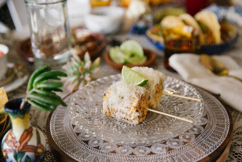 Close up shot of two cobs of chargrilled corn topped with cheese and lime - Australian Stock Image