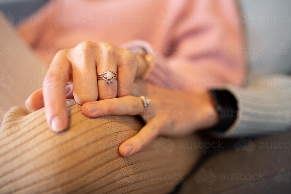 Close up shot of two women's hands holding each other showing wedding rings - Australian Stock Image