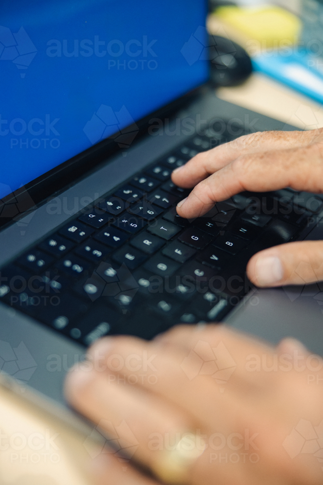 Close-up view of hands actively typing on a laptop keyboard - Australian Stock Image