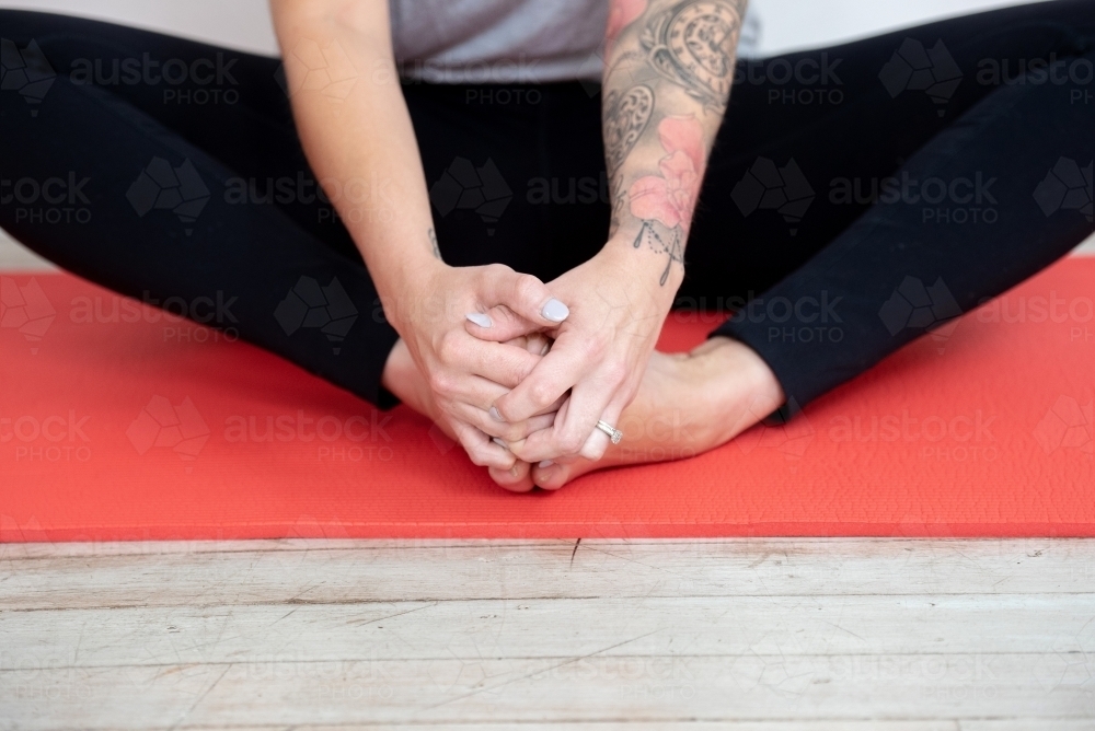 close up woman doing yoga stretching hands holding feet - Australian Stock Image