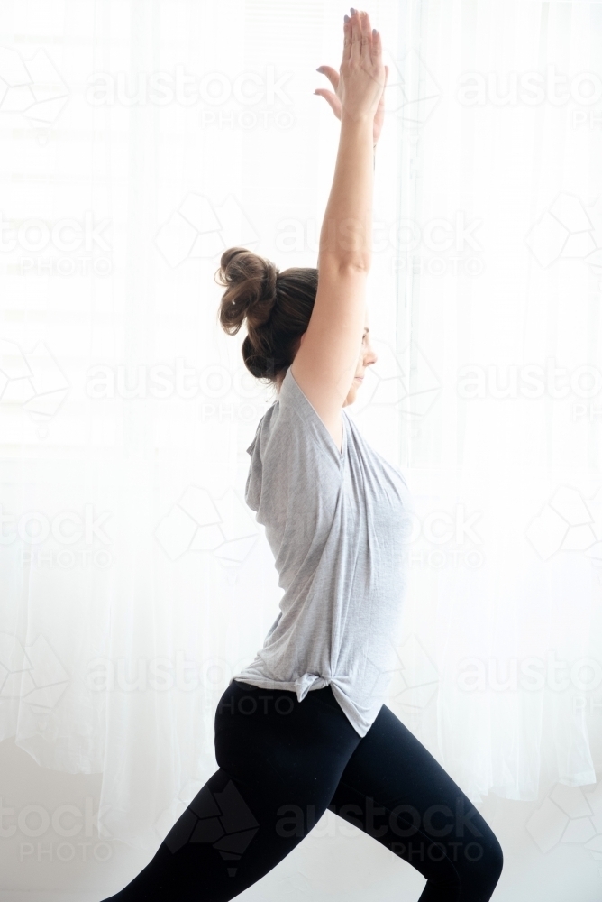 close up woman in warrior yoga pose side on white background - Australian Stock Image
