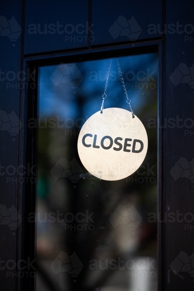 Image of Closed sign hanging in glass pane of shop front door ...