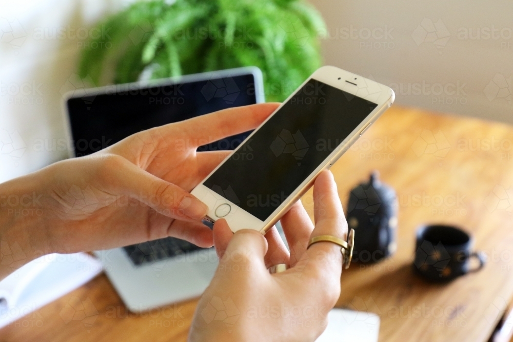 Closeup detail of female hands holding a smart phone inside an office - Australian Stock Image