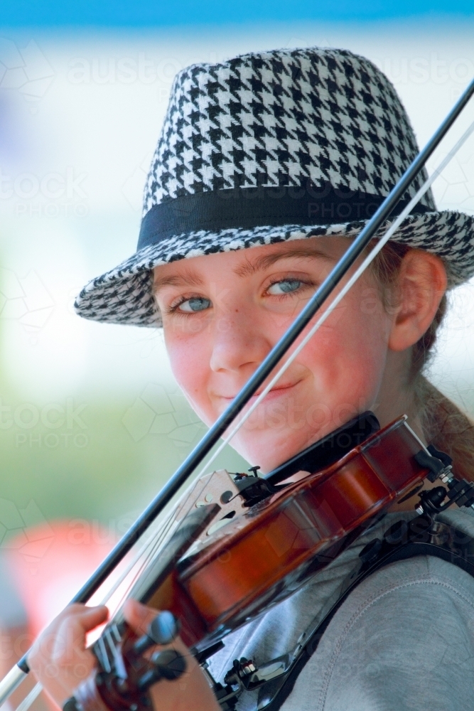 Close-up of a young girl in her early teens busking with a violin. - Australian Stock Image