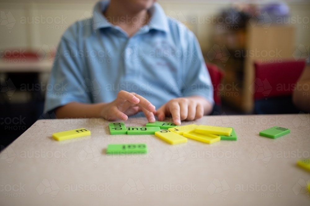 Closeup of primary school student's hands working with green and yellow word tiles - Australian Stock Image