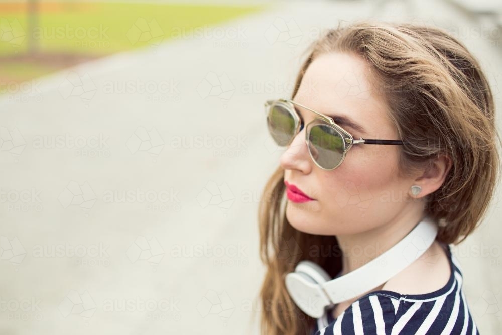 Closeup of young woman with headphones and sunglasses - Australian Stock Image