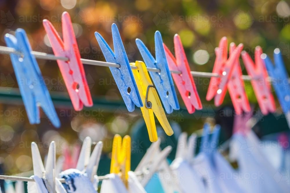 Image of Clothes pegs holding laundry on a line Austockphoto