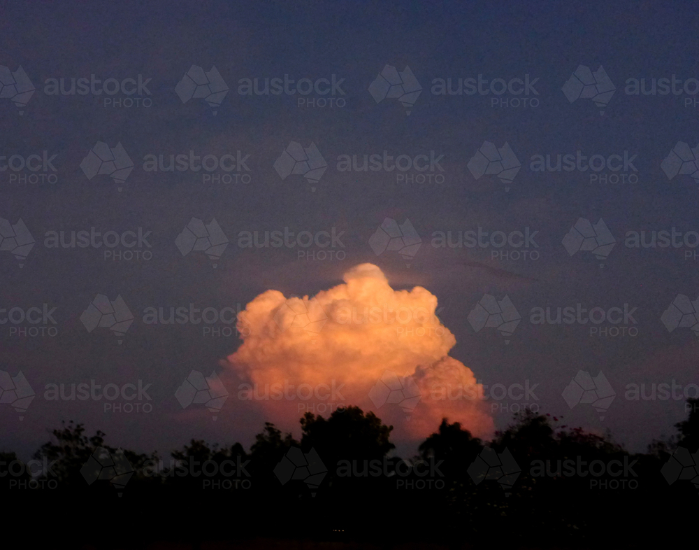 Cloud formation illuminated in golden orange against the night sky - Australian Stock Image