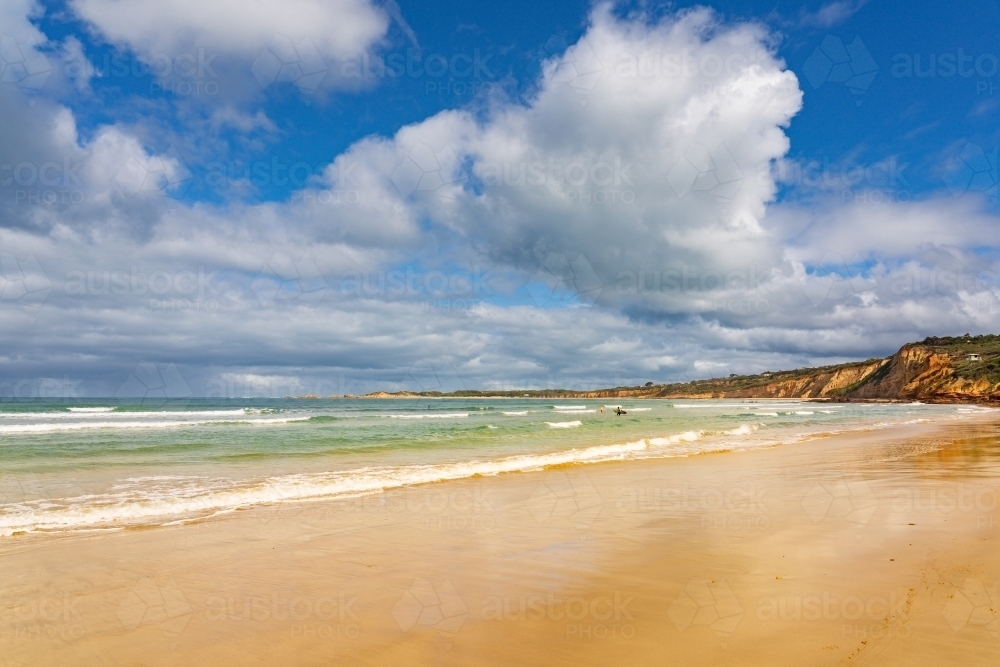 Clouds in a blue sky over a wide golden sand beach - Australian Stock Image