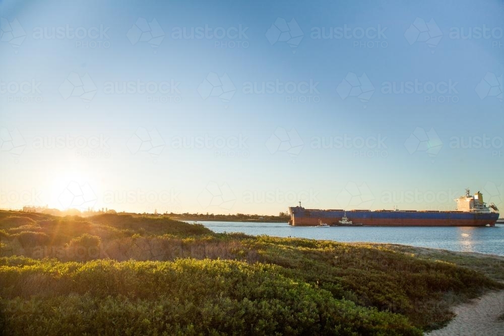 Coal ship coming into Newcastle Harbour at sunset - Australian Stock Image