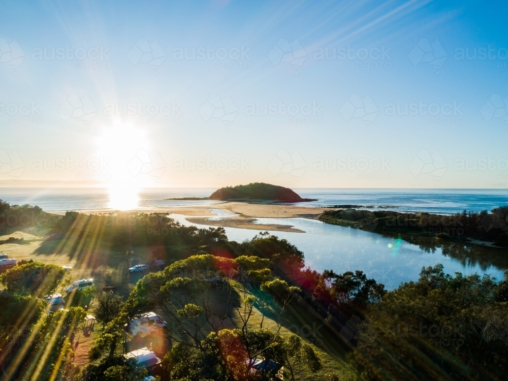 Coastal caravan park with sun rising over the ocean and river mouth - Australian Stock Image