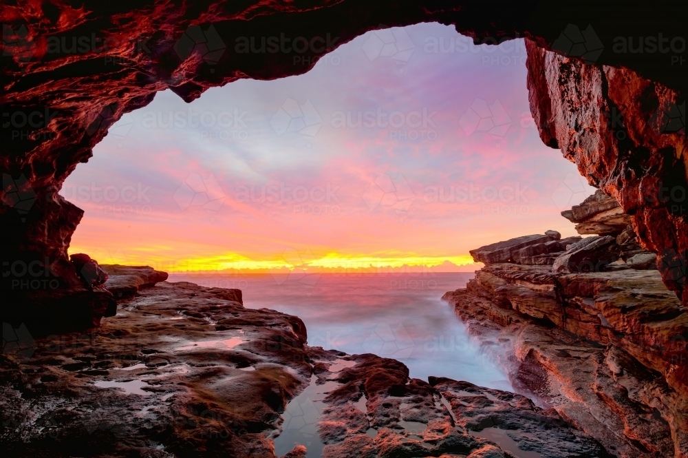 Coastal cave arch views to glorious full colour sunrise over the ocean - Australian Stock Image