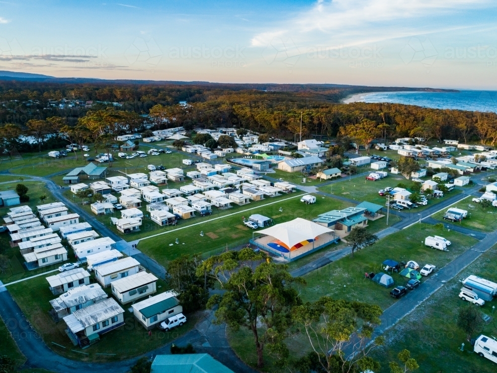 Coastal holiday caravan park at dusk with rows of cabins for accommodation and camping sites - Australian Stock Image