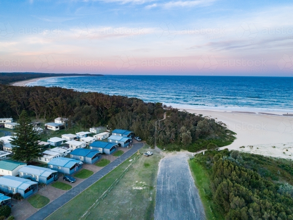Coastal holiday caravan park with cabins and path to beach at dusk - Australian Stock Image
