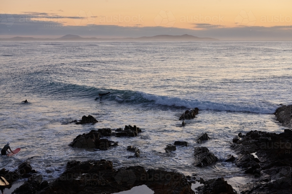 Coastal landscape on sunrise with surfers - Australian Stock Image