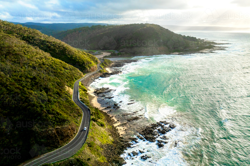 Coastal road winding past cliffs and turquoise surf - Australian Stock Image