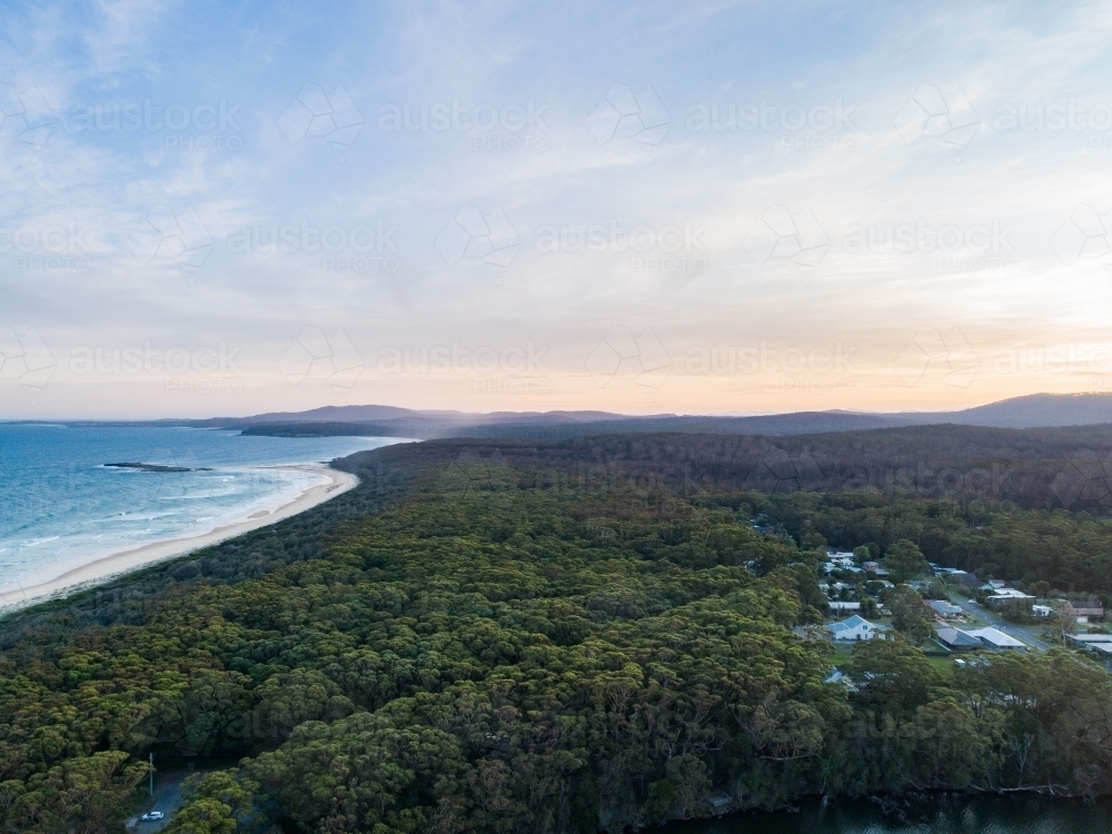 Coastal scene at dusk forest running down to empty sandy beach - Australian Stock Image