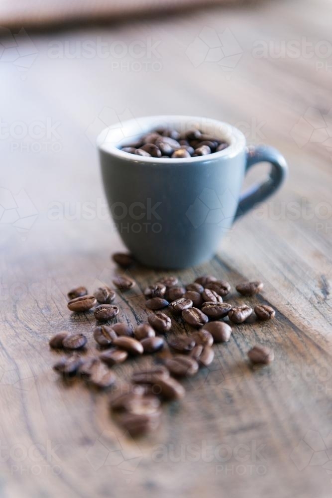 Coffee beans and cup with wood grain table background - Australian Stock Image