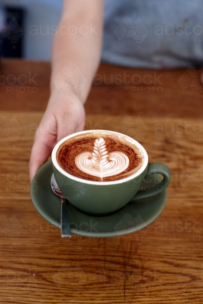 Coffee with froth decoration served on table - Australian Stock Image