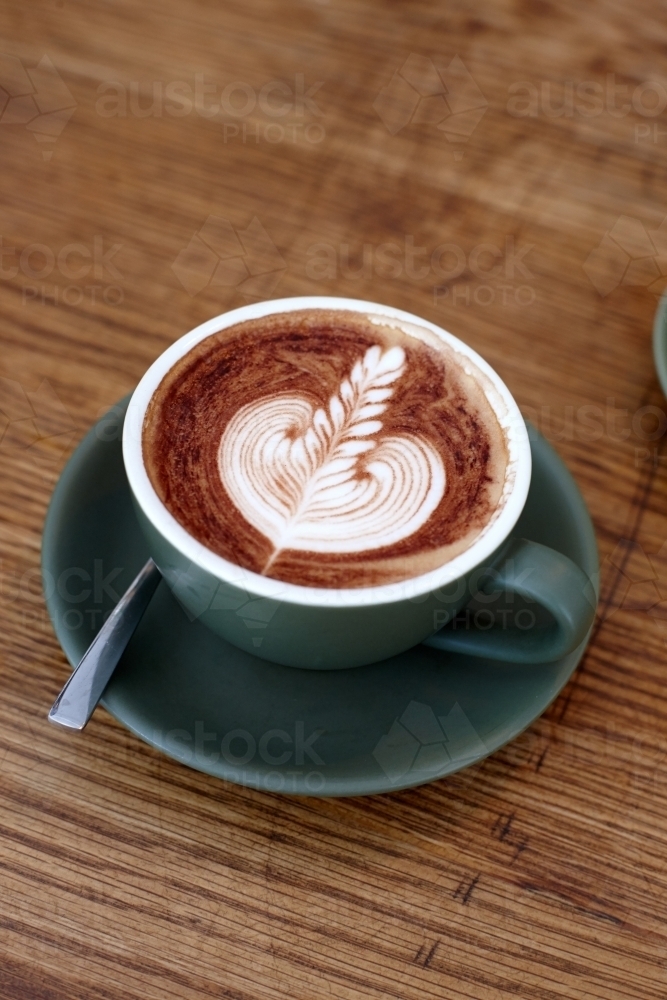 Coffee with froth decoration served on table - Australian Stock Image