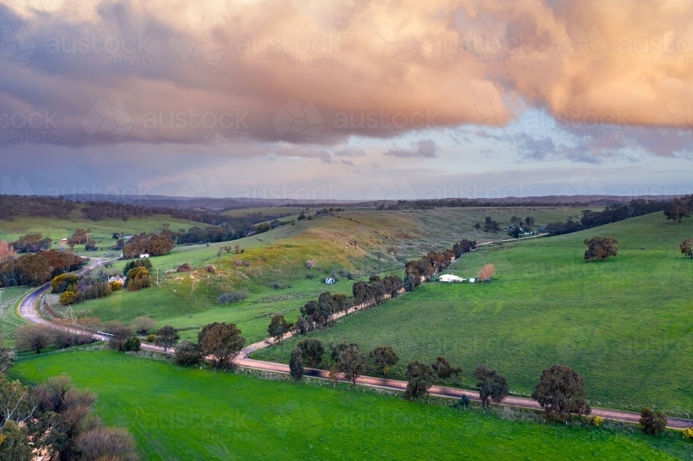 Colored cloud formations over country roads and green rural countryside - Australian Stock Image