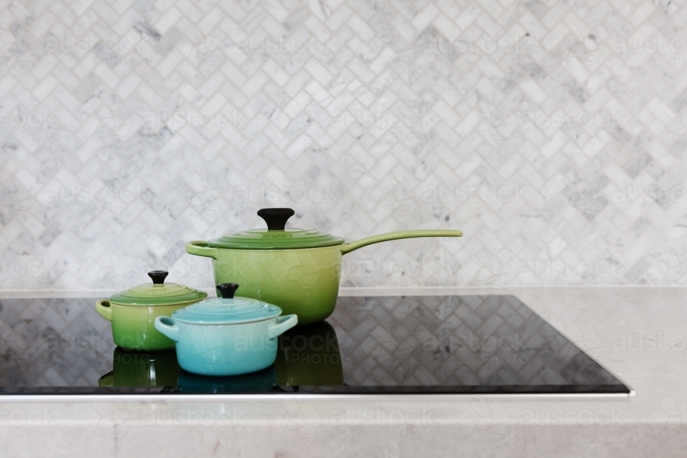 Colorful pots on display on a stove top - Australian Stock Image