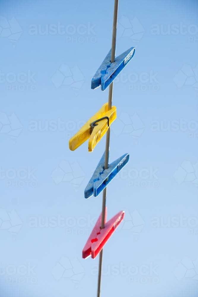 Coloured clothes pegs hanging on a line - Australian Stock Image