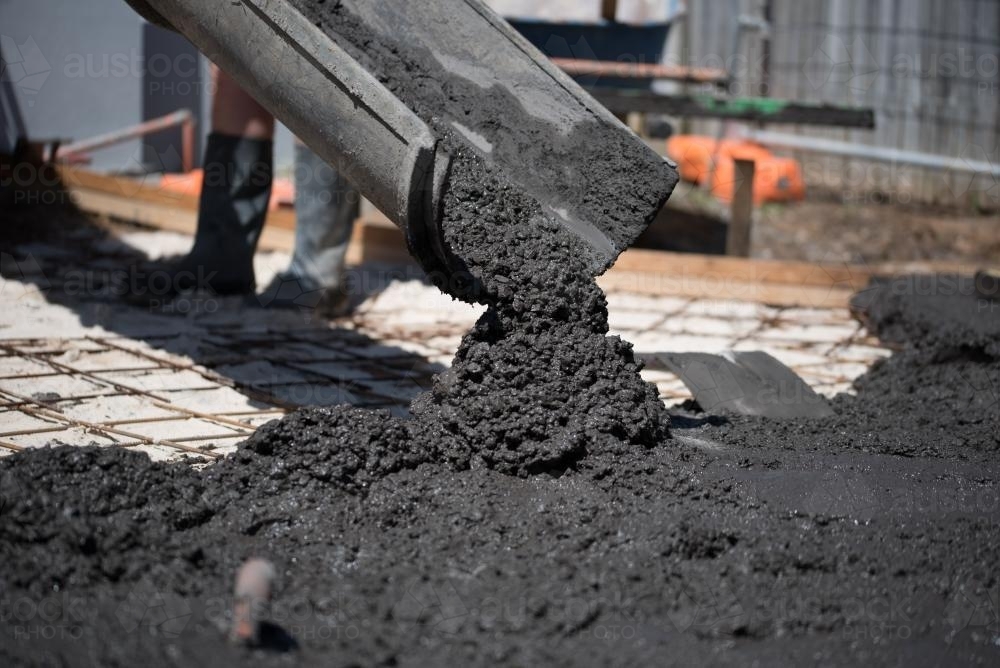 Image of Coloured concrete pouring out of cement truck chute - Austockphoto