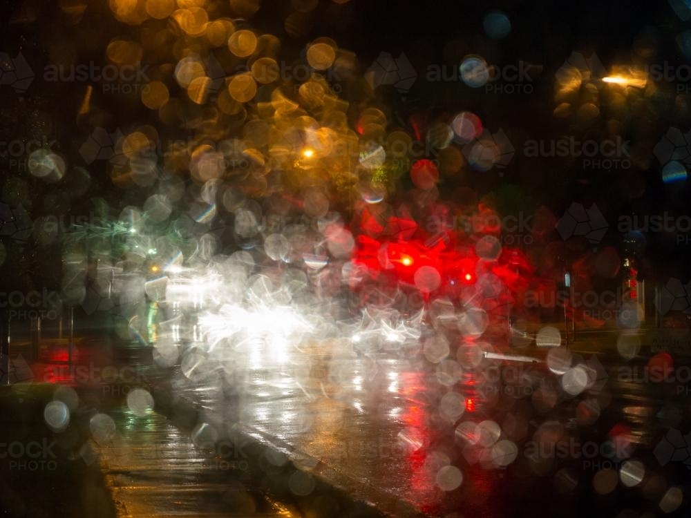 Colourful city light patterns distorted by rain on a car windscreen - Australian Stock Image