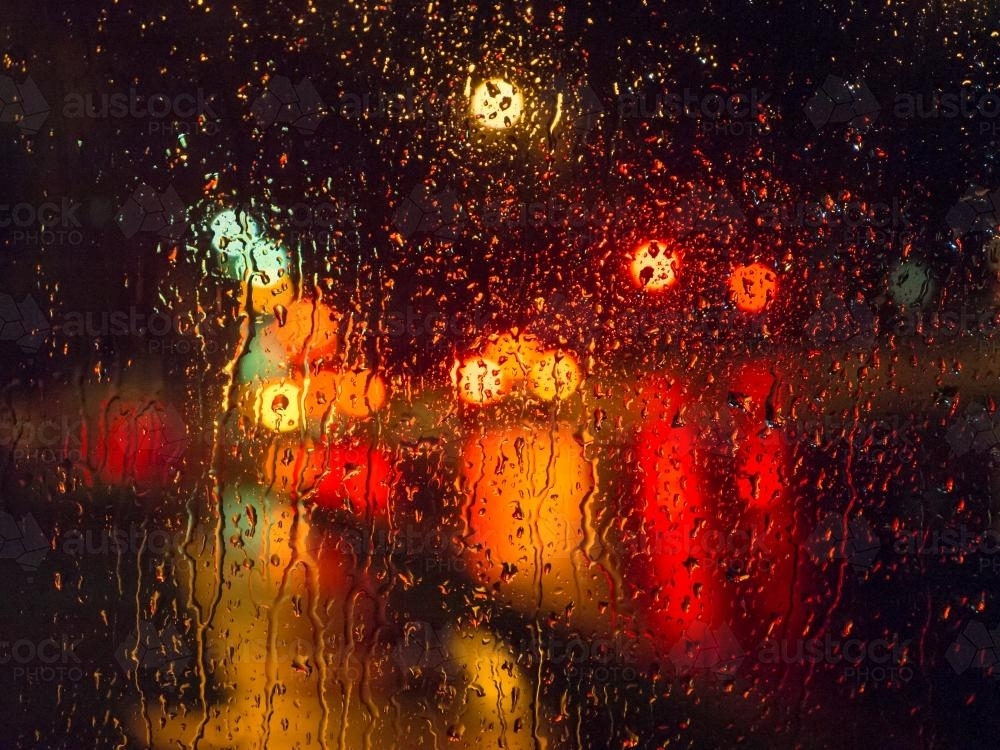 Colourful city light patterns distorted by rain on a car windscreen - Australian Stock Image