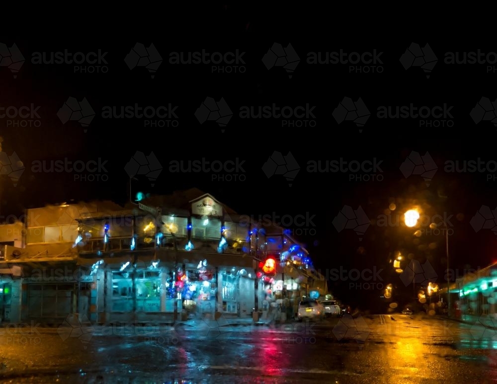 Colourful distorted lights of a building on a wet street at night - Australian Stock Image