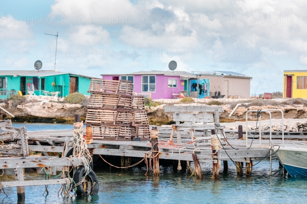 Colourful fishing shacks, old wooden jetty with stacks of commercial craypots - Australian Stock Image