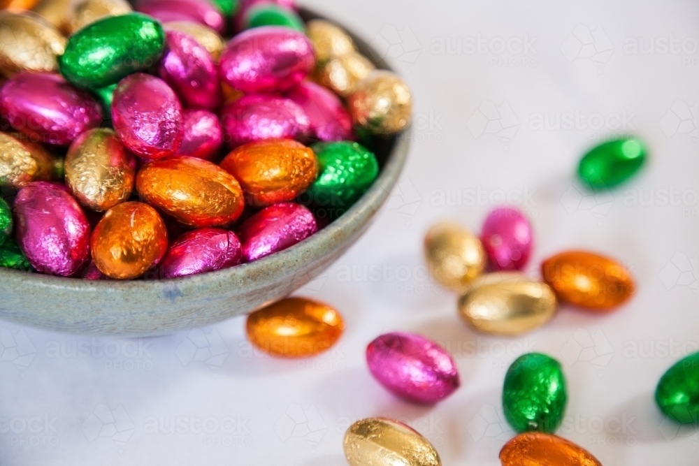 Image of Colourful, foil wrapped Easter eggs in a bowl on white