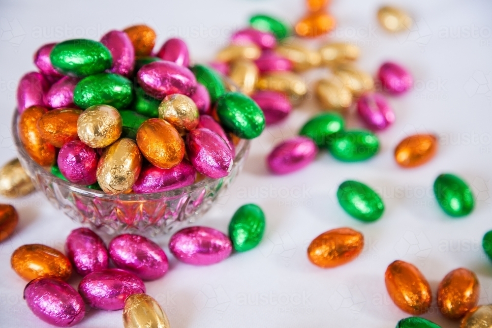 Image of Colourful, foil wrapped Easter eggs in a bowl on white