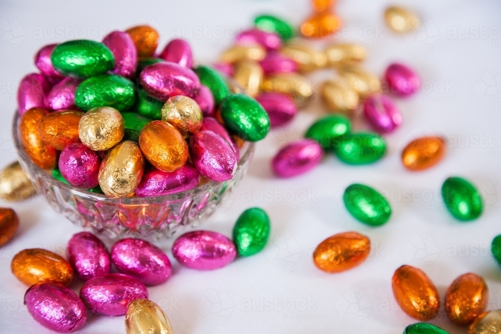 Colourful, foil wrapped Easter eggs in a bowl on white - Australian Stock Image