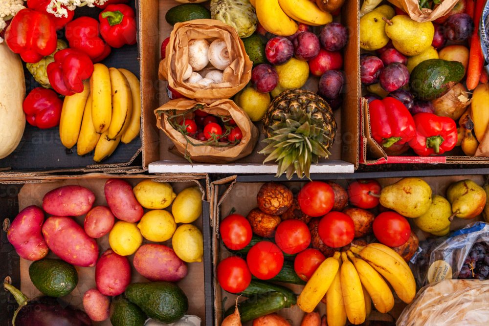 Colourful overhead angle of fresh organic fruit and vegetable boxes at unsupermarket food hub - Australian Stock Image